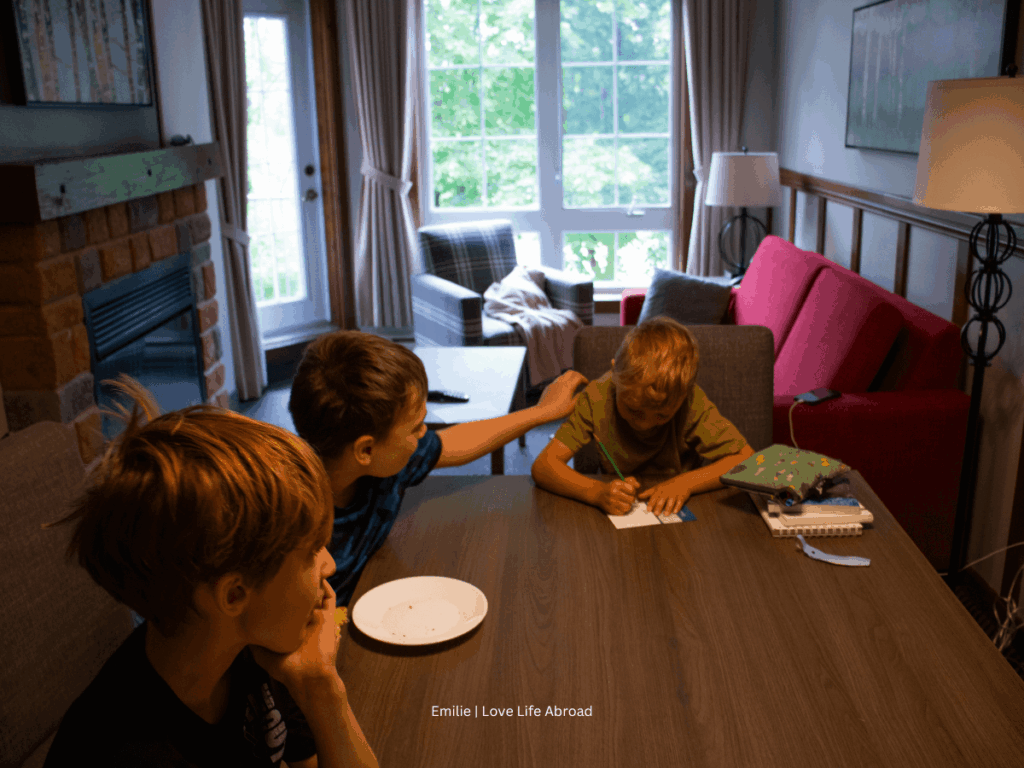The kids playing a game in the living room/dinner room in the One-bedroom suite at La Tour des Voyageurs