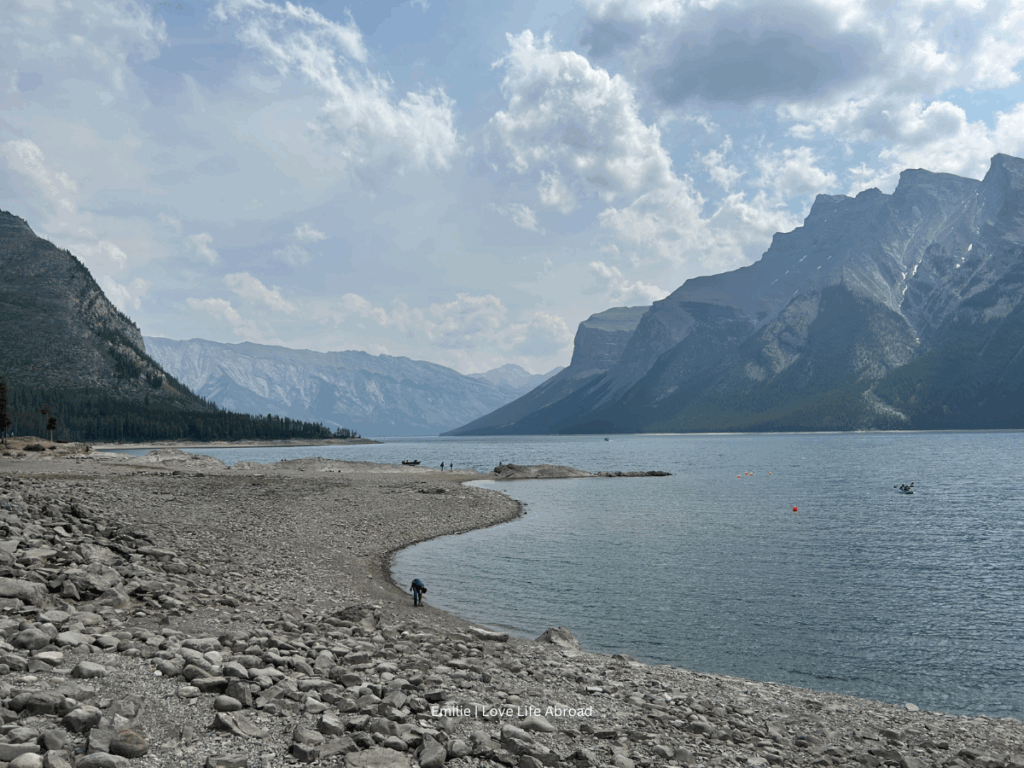 A rocky beach with mountains in the background. It's Lake Minnewanka in Banff National Park