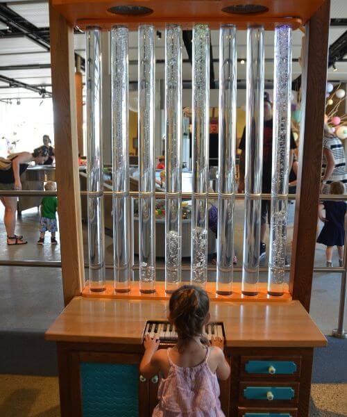 A girl playing with a unique piano at TELUS Spark in Calgary Photo credit Jen from AlbertaMamascom