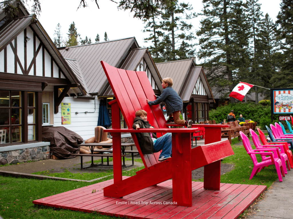 Kids climbing on the big red chair near The Boardwalk at Riding Mountain NP