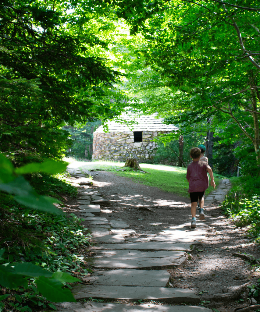 The kids running on the trail at the Lone Shieling to be the first to see the Scotish building